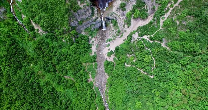 Tilt-up, zoom shot of a massive multi-tiered waterfall in Utah in the middle of a large forest. 4K footage, colored and ready to use.
