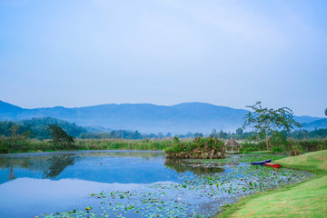 Landscape view of nature water lake green grass boats and mountain background in thailand.