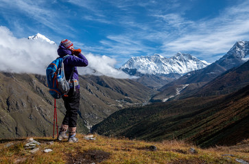 Fototapeta na wymiar Active hiker hiking, enjoying the view, looking at mount Everest and use use mobile phone