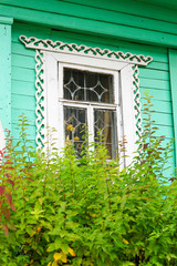 window with carved platbands in a green wooden house