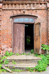old wooden door in brick wall of abandoned house