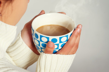 warm cup of hot coffee warming in the hands of a girl