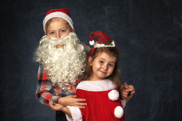 Children in Christmas outfits on a dark background in the Studio . Brother and sister on Christmas eve