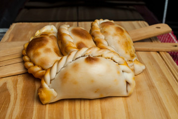 Wooden table with fresh homemade Empanadas (detailed close-up shot; selective focus)