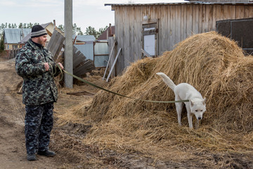 A man in overalls for a walk with a dog