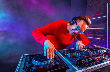 Cheerful Dj mixing tracks on a turntable in the night club