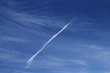 Fototapeta na wymiar smoke airplane flying over the blue sky and clouds