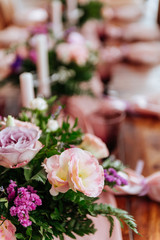 Vintage festive table setting with pink roses, candles and cutlery on an old wooden board