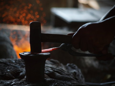 The blacksmith is making knives with heat from the fire.