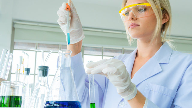 close up face of female scientist holding a tube and beaker with liquid substance. woman research is working in the Laboratory.