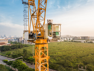 Aerial view of construction crane's control room with green park view background.