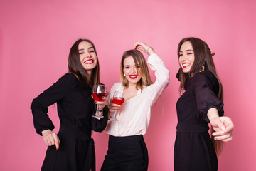 Two beautiful girls celebrate corporate party. Girls smiling, posing and dancing on pink background, bright makeup, red lips