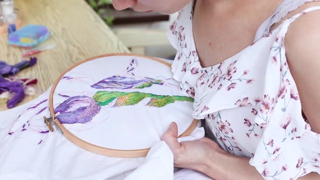 Female hands with vitiligo sewing with needle. embroidery hoop, embroidered fabric with colorful pattern. top view, close up. Traditional hobby, lifestyle. Needlework, handicraft