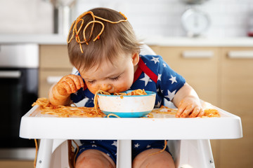 Messy baby eating pasta straight from bowl