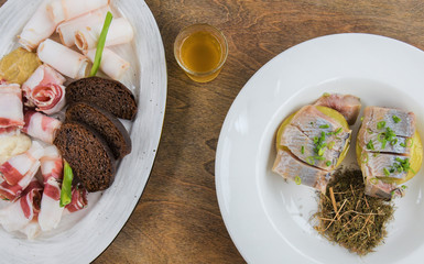 Top view, 2 dishes with appetizers: bacon, black bread, herring, potatoes, tincture.
