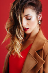 Fashion portrait of young woman in jacket and red swimsuit. Pink background, studio shot