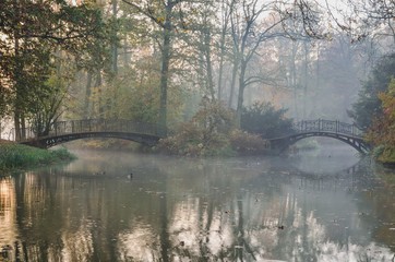Beautiful morning autumn landscape. Charming bridges in the park by the pond in Pszczyna, Poland.