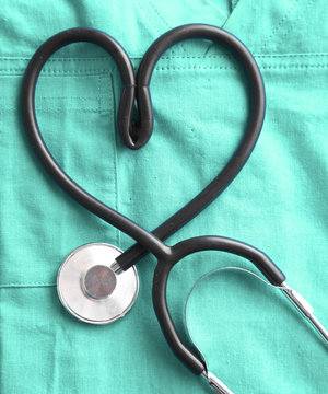 stethoscope shaping heart and clipboard on medical uniform, closeup