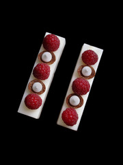 White mousse desserts with raspberries and meringues on brownie base flat lay
