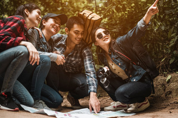 The Asian Friends Tour group looking at the map, looking for hiking directions and enjoys travel hiking in the forest and looking at animals, traveling and resting concepts.