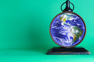 Time to protect the planet,save energy, save water,do not litter. Daylight Saving Time Started Or Ended. Globe and clock on a green background. Space for text. Elements of this image furnished by NASA