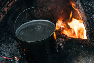 Tourist pot over the fire. Cooking in aluminum cookware. Survival in the wild.
