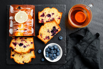 Homemade Blueberry Lemon Cake on black stone background.