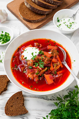 Beetroot soup - Traditional Ukrainian or Russian borscht with sour cream in a white bowl.