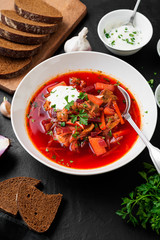 Beetroot soup - Traditional Ukrainian or Russian borscht with sour cream in a white bowl.