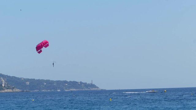 Speedboat is driving with a parachute at the end of a rope on the Mediterranean.