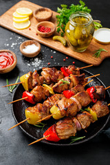 Kebabs - grilled meat skewers, shish kebab with vegetables on black wooden background.