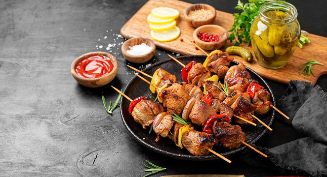 Kebabs - grilled meat skewers, shish kebab with vegetables on black wooden background.
