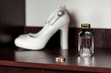 Three gold wedding rings and white high heel shoe on the table