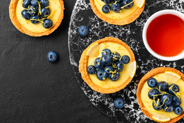 Blueberry tartlet, pie, tart with lemon custard. Black stone background.