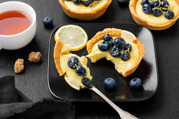 Blueberry tartlet, pie, tart with lemon custard. Black stone background.