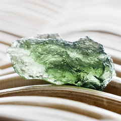 Macro photography of a moldavite stone on a wicker background