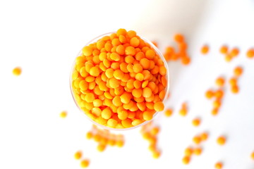 Red lentils on white background. Different forms of dry lentils. Lentils red in a transparent glass jar. Handful of legumes.