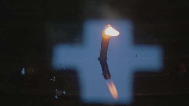 Wax candle and cross on a water surface in a Christian Chapel.