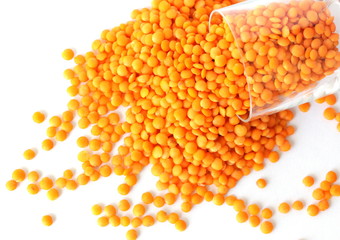 Red lentils on white background. Different forms of dry lentils. Lentils red in a transparent glass jar. Handful of legumes.