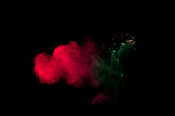 Colorful powder explosion on black background. Red green dust splash.