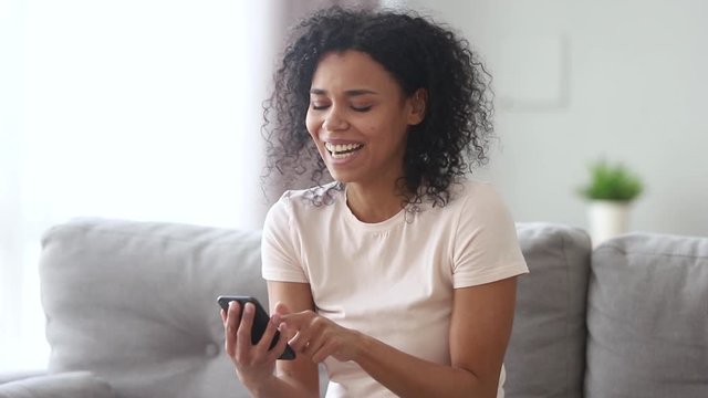 Laughing african woman holding smartphone read anecdote feels overjoyed