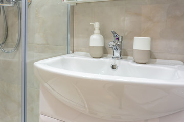 Soap and shampoo dispensers near Ceramic Water tap sink with faucet in expensive loft bathroom