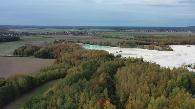 Aerial view of open pit kaolin clay mine (kaolinite quarry) surrounded by autumn landscape with colorful trees - landscape panorama of Poland from above, Europe