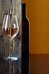 Bottle and glass of white wine on a black table.