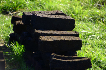 stack of fresh vintage peat blocks in autumn sun, peat briquettes on pile