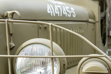Close-up view of a US Army World War 2 truck, shown in its restored condition. Details of the headlight and engine cowling can be seen. - obrazy, fototapety, plakaty