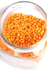 Red lentils on white background. Different forms of dry lentils. Lentils red in a transparent glass jar. Handful of legumes.