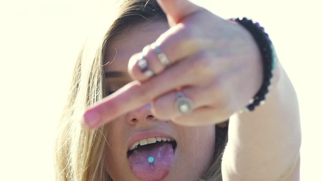 Cute blonde millennial woman gives middle finger to camera. Extreme close up, handheld.