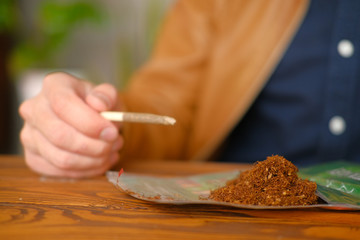 Young guy makes cigarette with hand rolling tobacco