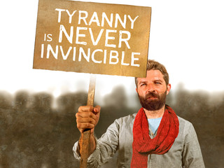 attractive hipster with scarf and beard protesting at political demonstration holding billboard...